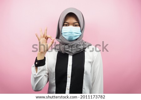Muslim women wearing medical masks, anti corona virus movement, anti covid-19 movement, health movement using masks, with hands showing ok sign, good work, success, victory, isolated