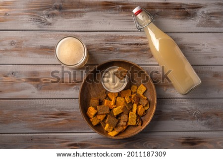 Top view homemade tradishional russian light rye kvass in bottle with glass cup and crackers on wooden background. Wonderful healthy refreshing drink for summer