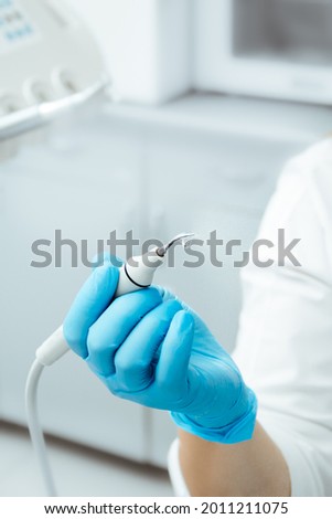 Dental ultrasonic scaler with water splash. Periodontal ultrasonic scaler. Dental instrument. Tartar removal. Dentist in blue gloves. Royalty-Free Stock Photo #2011211075