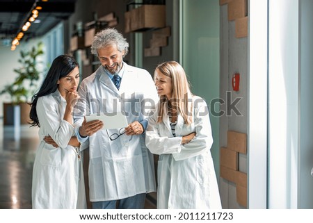 Group of medical staff discussing in clinic hallway. Healthcare professionals having discussion in hospital corridor. Medical staff discussing over medical reports in hospital
