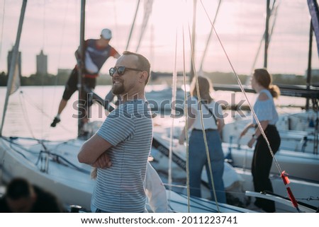 Preparation for the regatta at the yachting school at the marina with sailing yachts. Students and coaches prepare moored sports yachts for sailing on a sunny summer day. Royalty-Free Stock Photo #2011223741