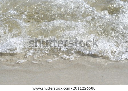 Photo of an ocean wave crashing in on shore on the beach