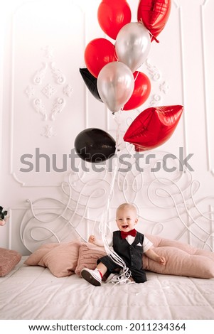 Happy child boy in bed with balls. Baby's birthday. Happy birthday concept