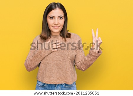 Young beautiful woman wearing casual clothes smiling swearing with hand on chest and fingers up, making a loyalty promise oath 