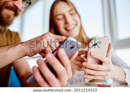 Blurred male and female bloggers checking mobile notification during friendly meeting for online networking in social media, millennial students reading web publications while browsing content Royalty-Free Stock Photo #2011254353