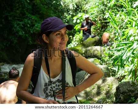 Latin Woman Using a Purple Cap is Sitting and Relaxing in the Middle of Nature