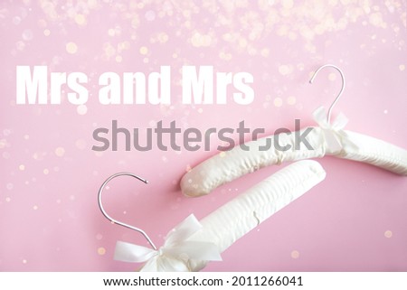Wedding satin hangers. Two empty white soft clothes hangers on a bright pink background with blur. Love concept with an inscription Mrs and Mrs