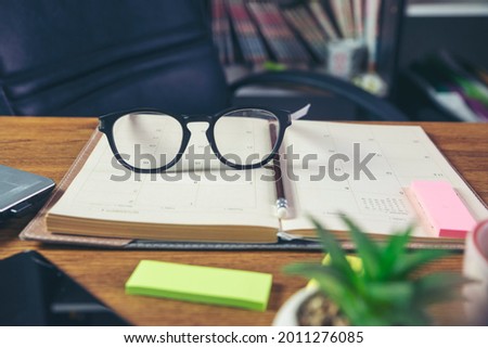 Desk for student education concept. Glasses, book, note pad placed on School table for student work online at home.