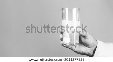 Glass of water tablet. Glass with efervescent tablet in water with bubbles. Close up of man holding a pill. Black and white.
