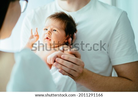 Unrecognizable parents with newborn baby girl. Close up portrait of two week old sweet new born baby attentively looking on her mother. Royalty-Free Stock Photo #2011291166
