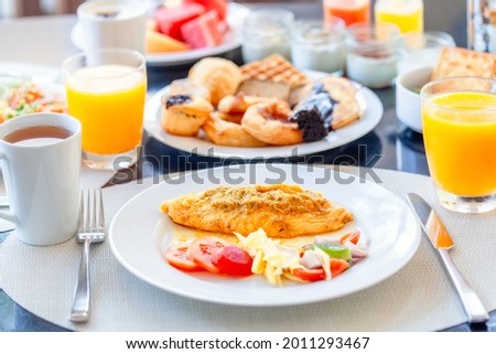 Breakfast Buffet in Luxury Hotel, Omelette and Fresh Desserts, Buns, Croissant. Dining Table with Plate of Delicious Food. Food in Hotel with Plates Full of Food, Orange Juice in Glass and Coffee Cups Royalty-Free Stock Photo #2011293467