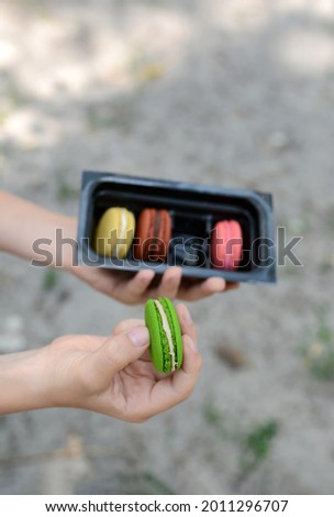 Delicious sweet multi-colored macarons in the hands of a boy. Popular dessert