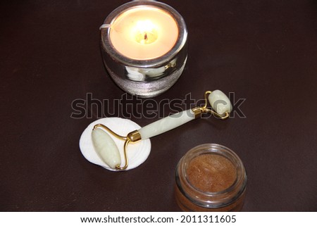 Burning candle, roller massager and body scrub