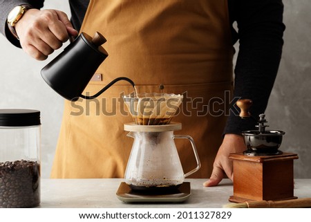 Men barista making a drip coffee, pouring hot water from kettle over a ground coffee powder Royalty-Free Stock Photo #2011327829