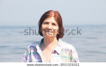 portrait of charming happy 72 year old woman by the sea in summer on a sunny hot day Royalty-Free Stock Photo #2011331012