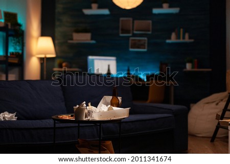 Chaotic empty living room of depressed person with scattered food mess, messy table. Unorganized house apartment of lonely woman with sever depression having garbage, rubbish with no people in Royalty-Free Stock Photo #2011341674