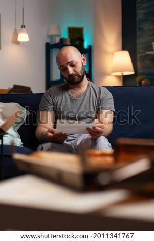 Anxious frustrated depressed young man reading letter, payment notification, bad financial report, renter problem, bank notice. Shocked, worried annoyed tenant by warning document for unpaid bills Royalty-Free Stock Photo #2011341767