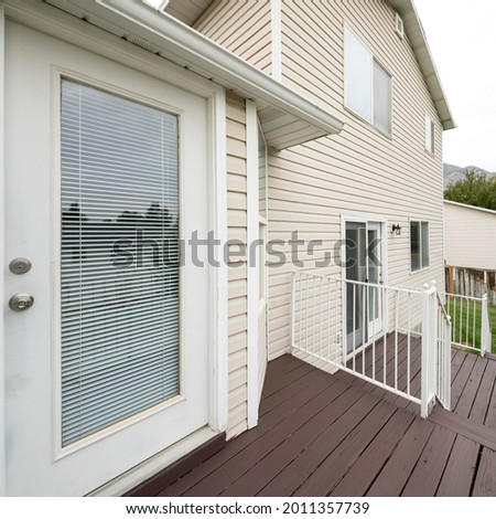 Square frame Exterior of a house with vinyl wood wall, elevated wooden deck and doors with glass panels