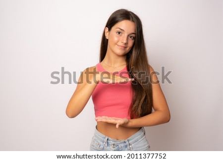 Young caucasian woman posing isolated holding something with both hands, product presentation.