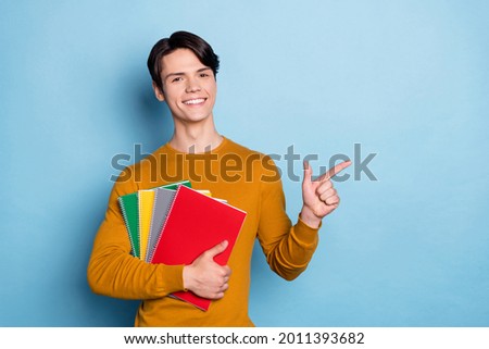 Photo of college a-student hold copybook direct finger empty space wear orange shirt isolated blue color background
