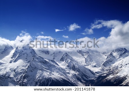 Snowy mountains at sun day. Caucasus Mountains. View from ski resort Dombay.