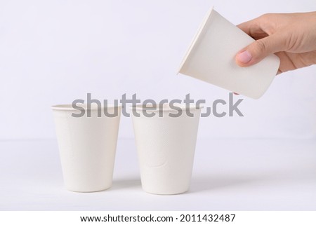 Biodegradable coffee cup made from natural fiber with hand on white background, Eco friendly and sustainability concept