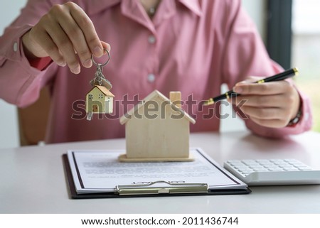 woman holding house keys real estate agent along with documents to rent or buy a house woman working home loan at her office