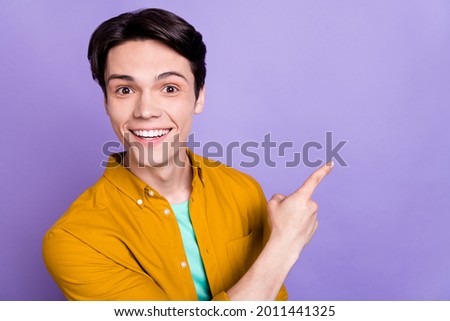 Photo of young man happy positive smile point finger empty space advert suggest direct isolated over violet color background