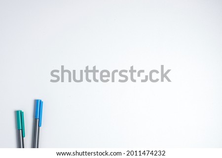 White background template with two blue and green colored pens as a complement