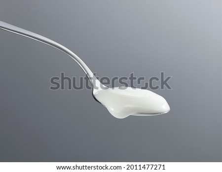 Spoon scooping yogurt isolated on gray background Royalty-Free Stock Photo #2011477271