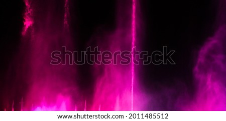 Splashing fountain in pink at night as background.