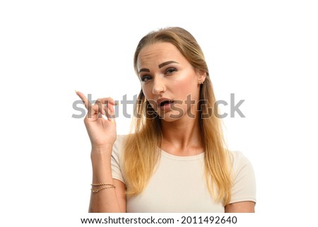 Portrait of a caucasian girl on a white isolate shows a finger to the side