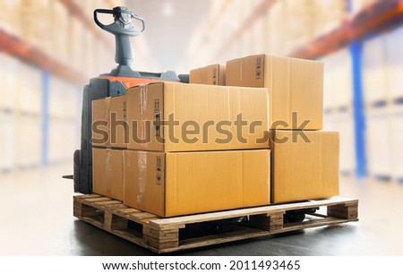 Package Boxes on Pallet with Electric Forklift pallet Jack Load at The Storage Warehouse. Supply Chain Storehouse, Shipping Warehouse Logistics. Royalty-Free Stock Photo #2011493465