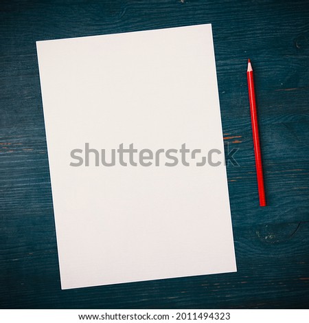 A blank white sheet and pencil for drawing on a wooden background with space for copying and lettering. Layout, mockup free space.
