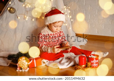 Little child using cell phone to video phone call to greeting his happy family for Xmas festival. Boy having a Christmas video call with Santa Clause. Celebrating Xmas online, conference in mobile.