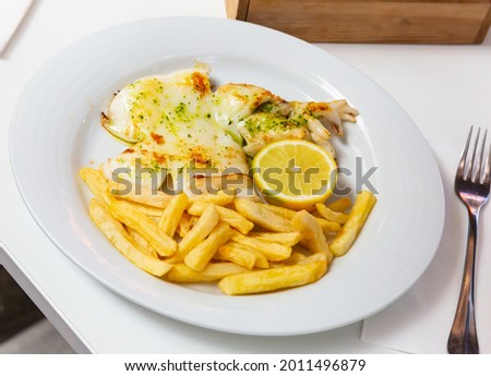 Picture of grilled tasty cuttlefish served with french fries at plate