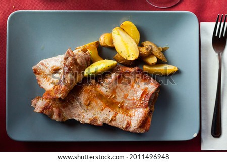 Picture of delicious fried iberian pork with fried potatoes at plate on table