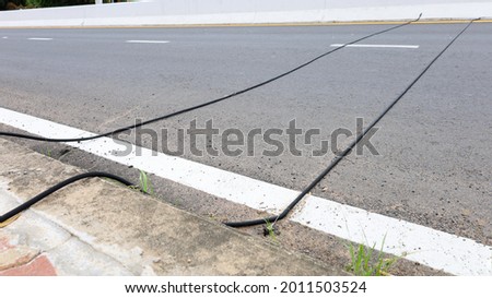 Dual black rubber tubes on the road. Air tube type traffic counter that can distinguish vehicle type and road speed with copy space. select focus Royalty-Free Stock Photo #2011503524