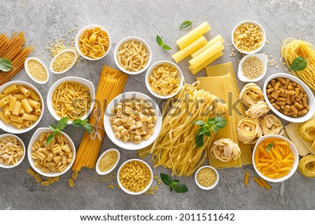 Pasta. Various kinds of uncooked pasta and noodles over stone background, top view with copy space for text. Italian food culinary concept. Collection of different raw pasta on cooking table Royalty-Free Stock Photo #2011511642