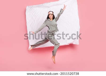 Full length photo of shiny adorable woman nightwear mask smiling jumping high isolated pink color background