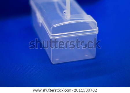 Small plastic container, organizer for storing small items. Photo on a blue isolated background 