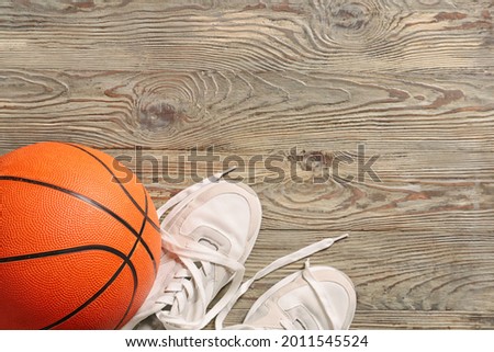 Ball for playing basketball game with shoes on wooden background