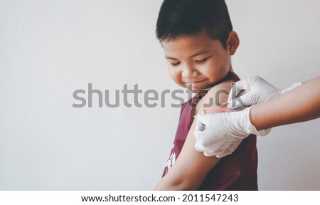 Asian boy showing his arm after against covid-19 with showing his arm getting plaster after got vaccine. Royalty-Free Stock Photo #2011547243