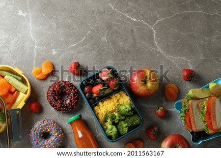 Lunch boxes with tasty food on gray textured table