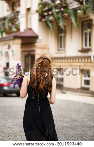 girl in black dress and purple flowers in the city