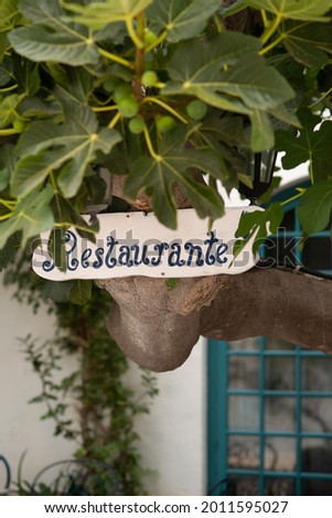 Wooden Restaurante Sign on a Tree in Front of an Al Fresco Cafe in Spain
