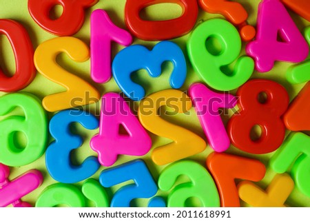 Colorful magnetic numbers on light green background, flat lay