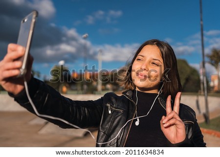Portrait of an adolescent girl taking a selfie making the v-sign.