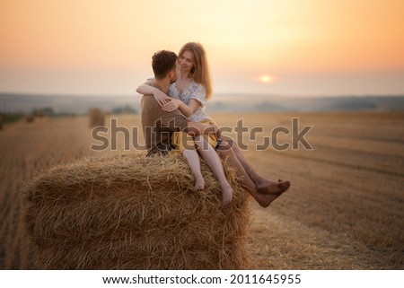 Photo of a couple in love in a field at sunset.