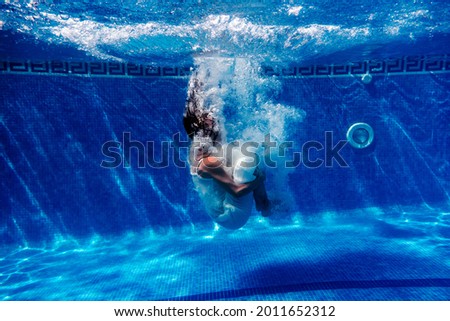 caucasian woman diving in swimming pool wearing white dress.underwater view. Summer time and vacation concept